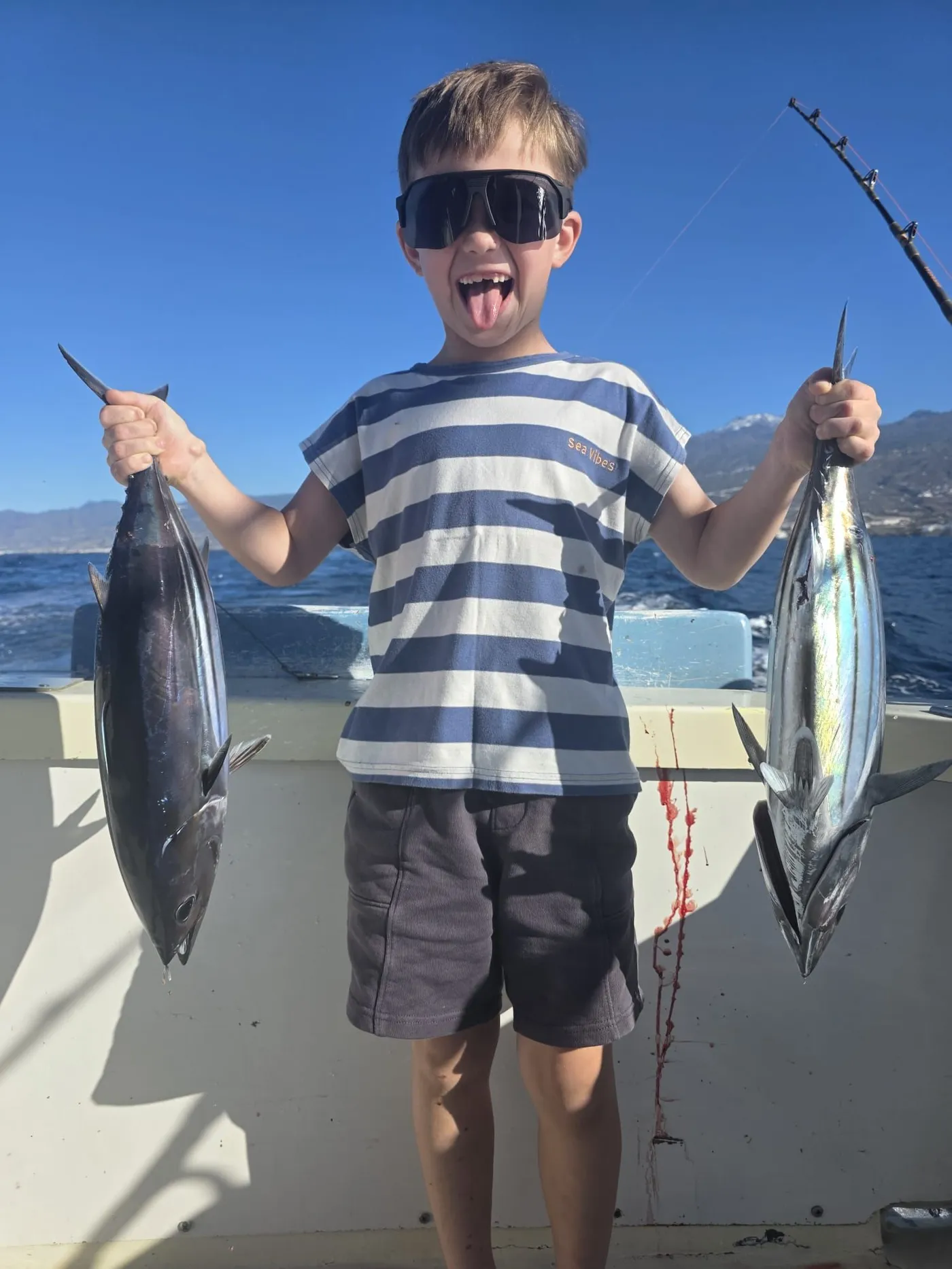 A young angler's catch off South Tenerife A young angler holding two tuna on a family fishing trip in Tenerife